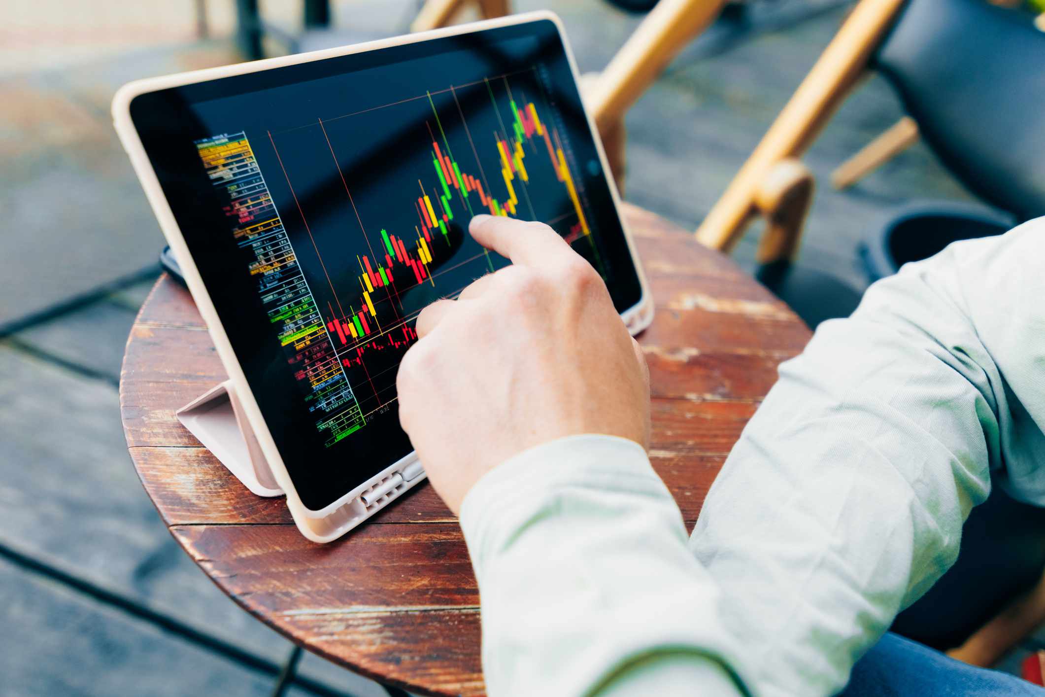 Men's hands and a trading chart on a digital tablet