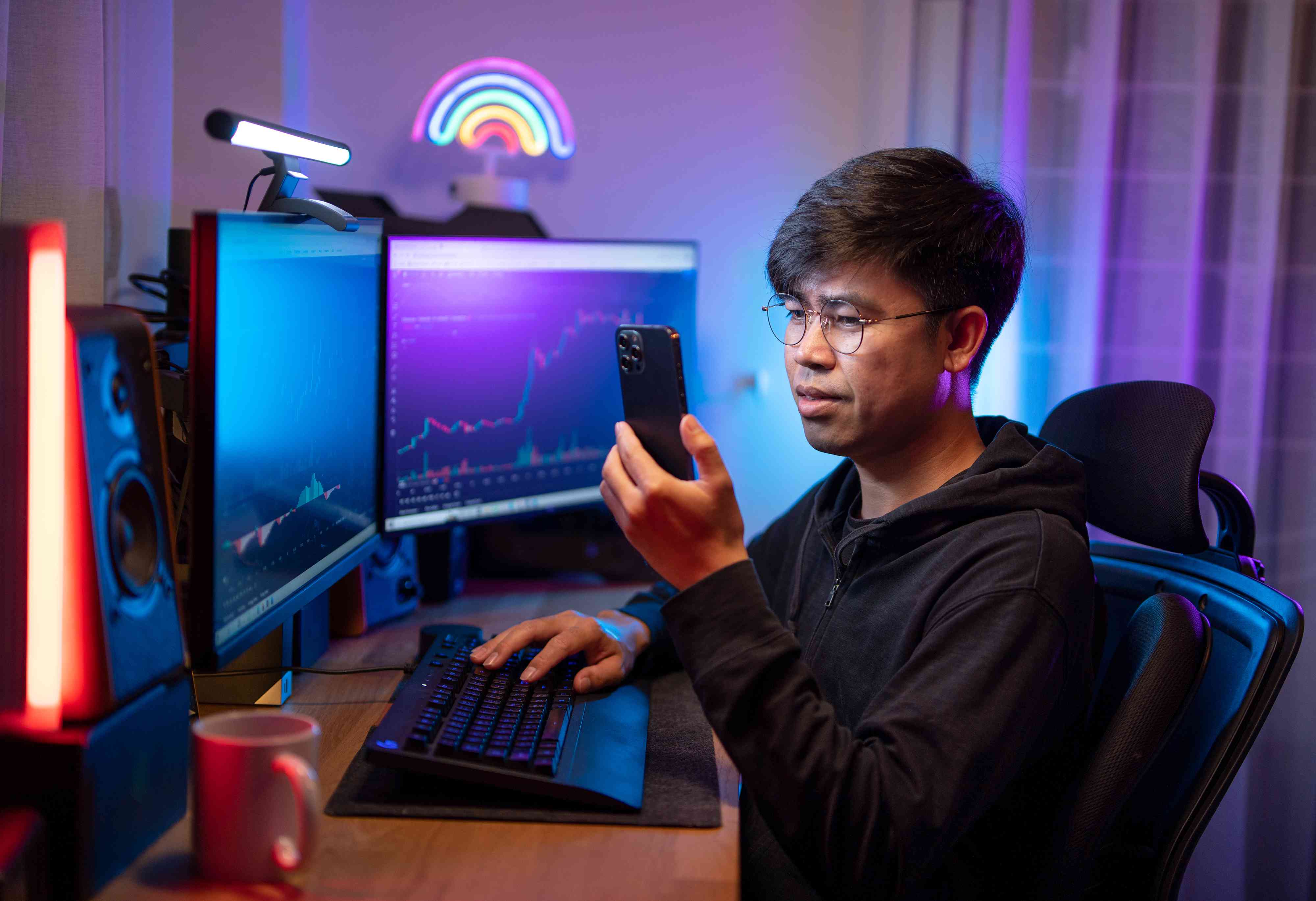 Young asian male trading and currency trading app on his smartphone