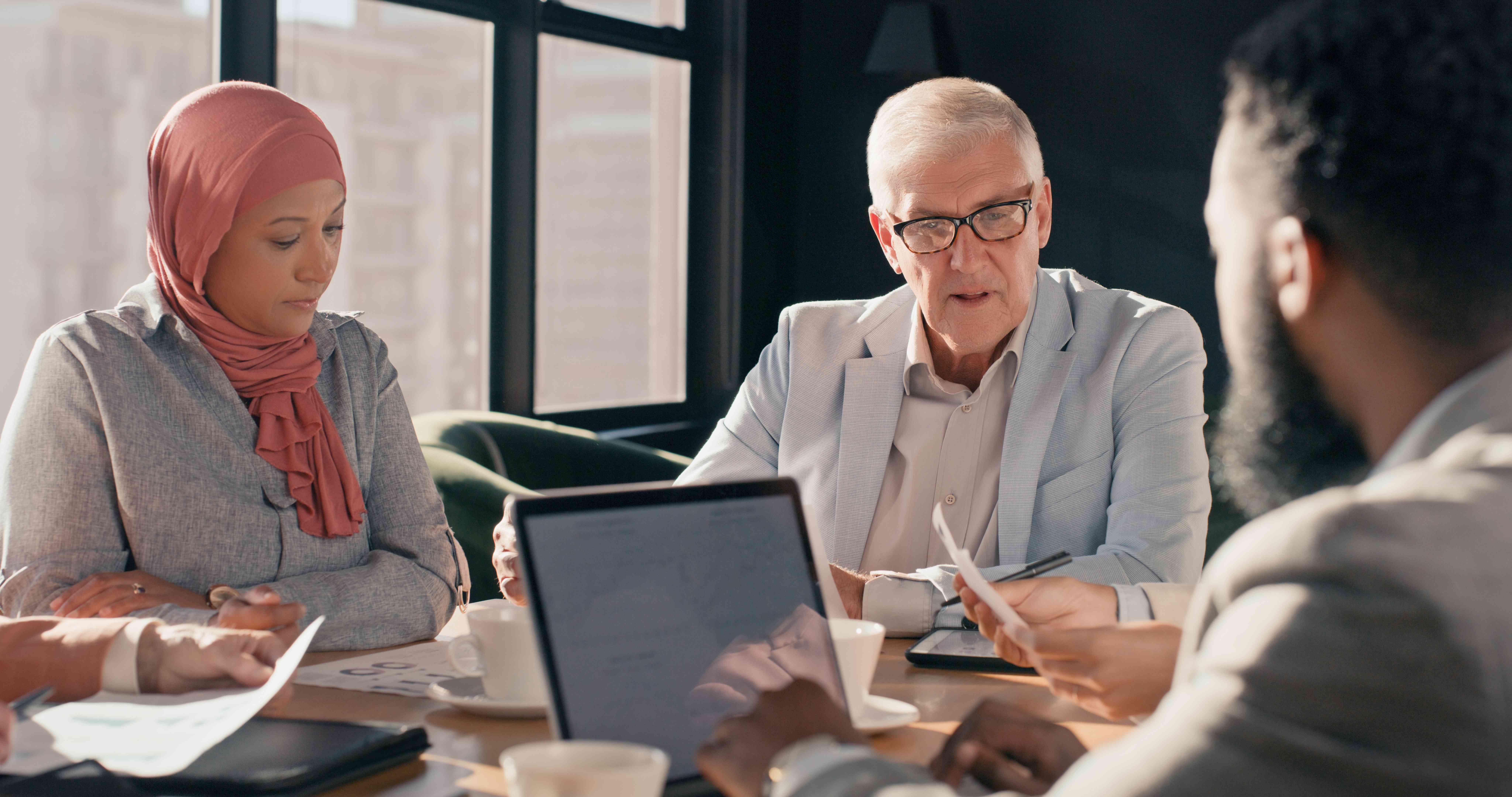 A investing couple talk to a financial advisor and compare potential funds by looking at the performance of the fund manager.