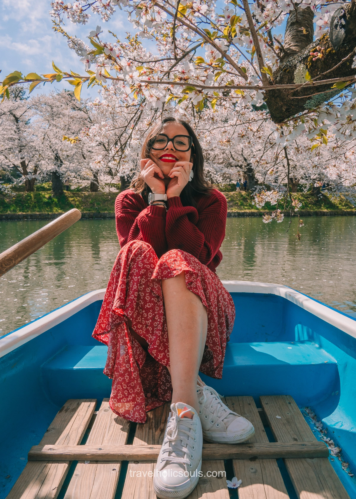 ragazza su barca circondata da alberi di ciliegio